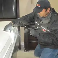 Bed bug inspection technician checking a mattress and bed frame for signs of infestation in Sacramento, CA