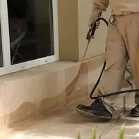 General pest control technician spraying exterior perimeter around a home in Sacramento, CA