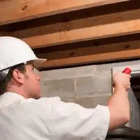 Termite inspection technician checking a basement wall and framing for termite activity in Sacramento, CA