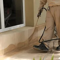 General pest control technician spraying exterior perimeter around a home in Sacramento, CA