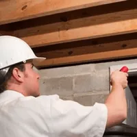 Termite inspection technician checking a basement wall and framing for termite activity in Sacramento, CA
